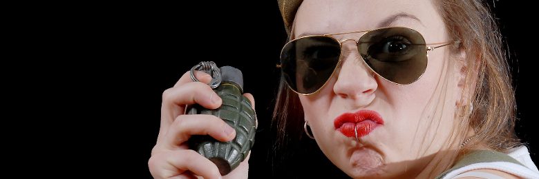 a closeup portrait of a young pretty female model with grenade in studio